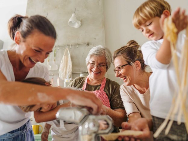 Family laughing while making pasta together