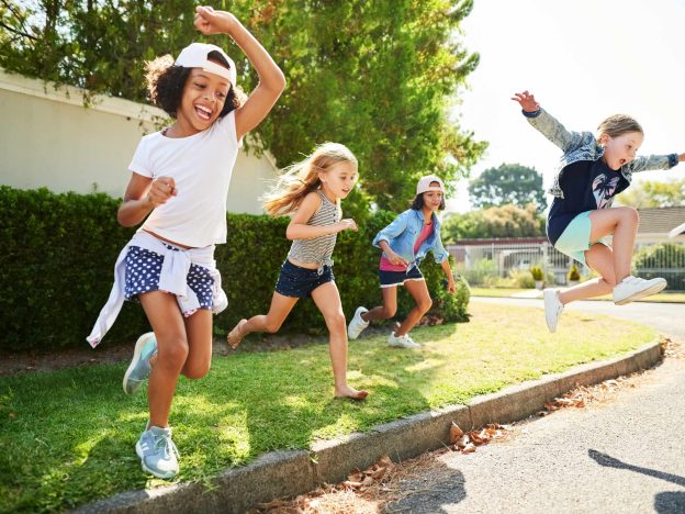 Happy kids jumping off a sidewalk in the sun