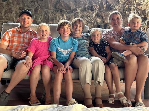 Grandmother surrounded by happy family on a couch.