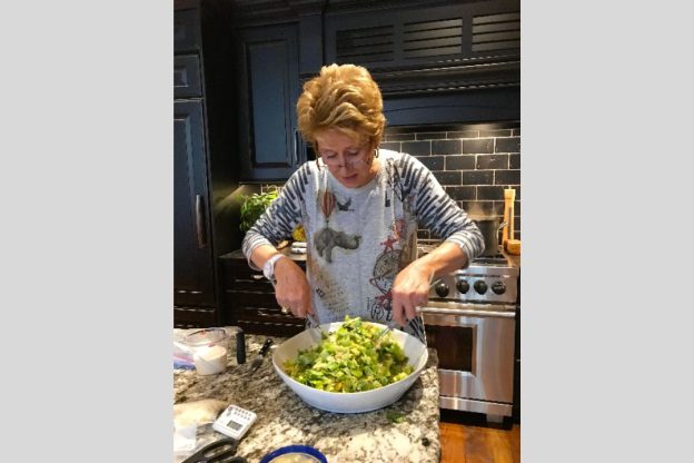 A woman tossing a large bowl of green salad