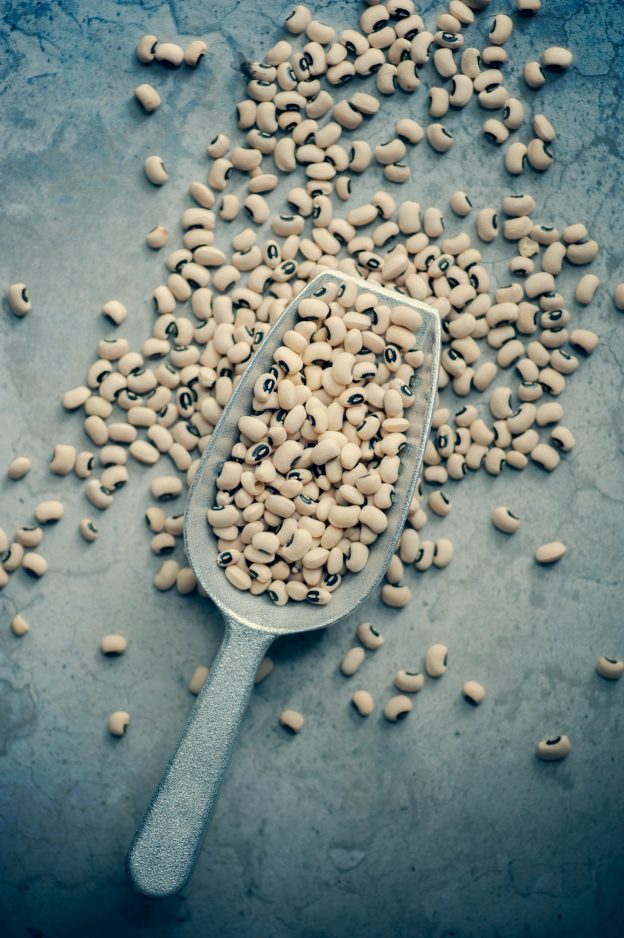 A metal scoop filled with scattered black eyed peas